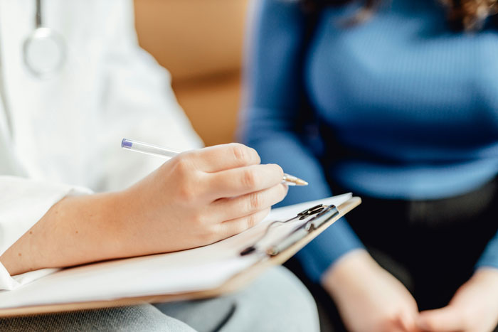 Medical professional writing on clipboard during consultation, highlighting patients privacy concerns in healthcare setting. - 9