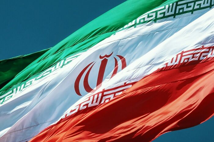 Iranian flag waving against a clear blue sky, symbolizing national identity amid resurged public anger.