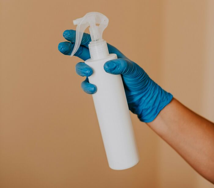 Hand in blue glove holding white spray bottle, related to messed up school incidents and hygiene concerns. - 10