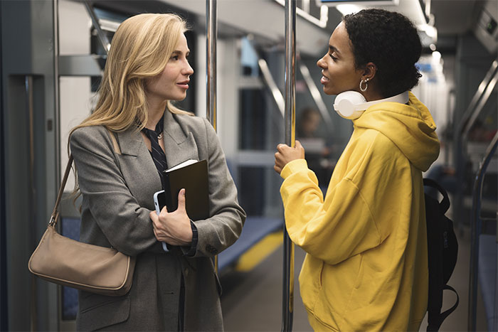 Two women having a conversation on public transit, illustrating cultural differences in things non-Americans do that confuse Americans. - 24