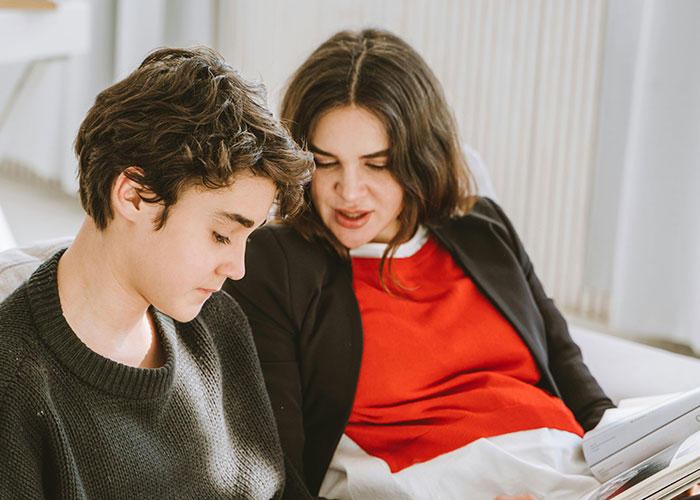 Two family members sitting on a couch sharing bizarre family stories they thought were completely normal.