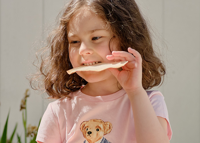 Child smiling while holding a cracker, illustrating humorous parents reveal hilarious lies they tell their kids.