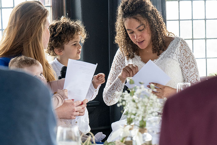 Bride in a white lace dress interacting with guests at a wedding, reflecting on neutrals and color choices.