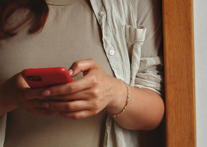 Woman rethinks her relationship holding a phone, showing concern after a red-flag argument with her boyfriend.