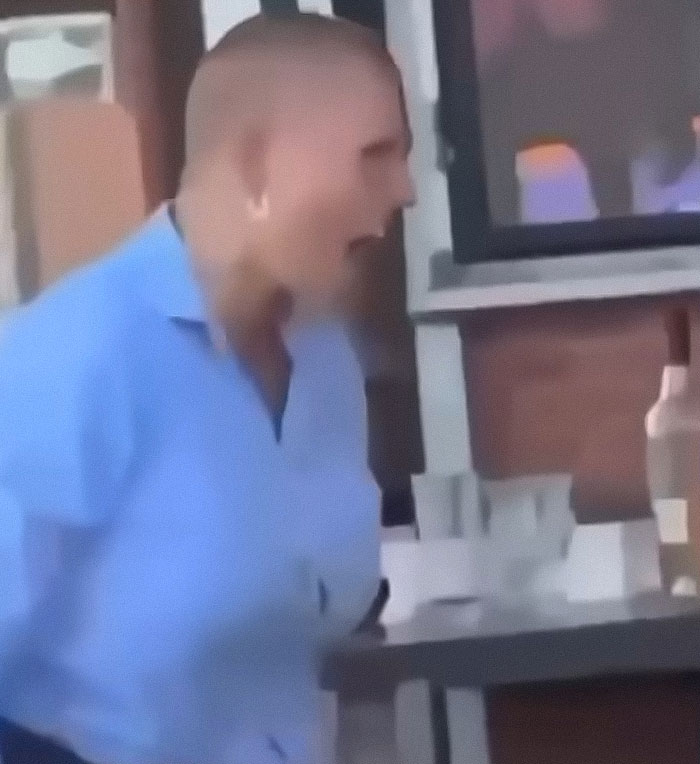 Reality star charged with murder speaking in a casual setting wearing a blue shirt near a bar counter.