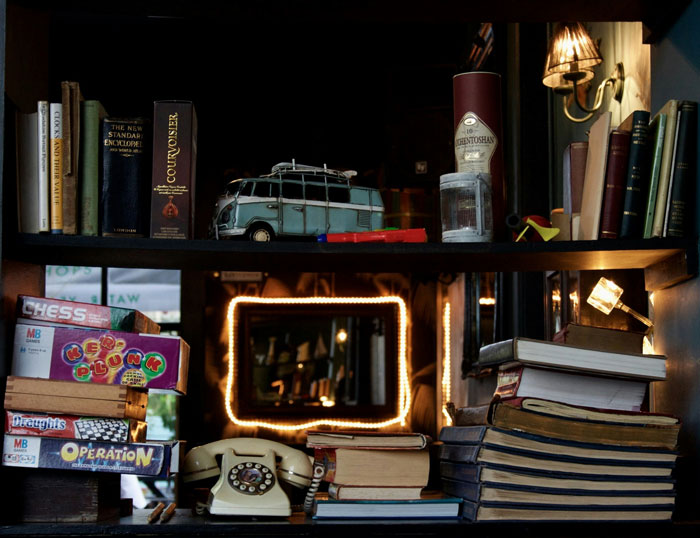 Vintage home decor display with old books, board games, rotary phone, and nostalgic items reflecting oldschool home trends.