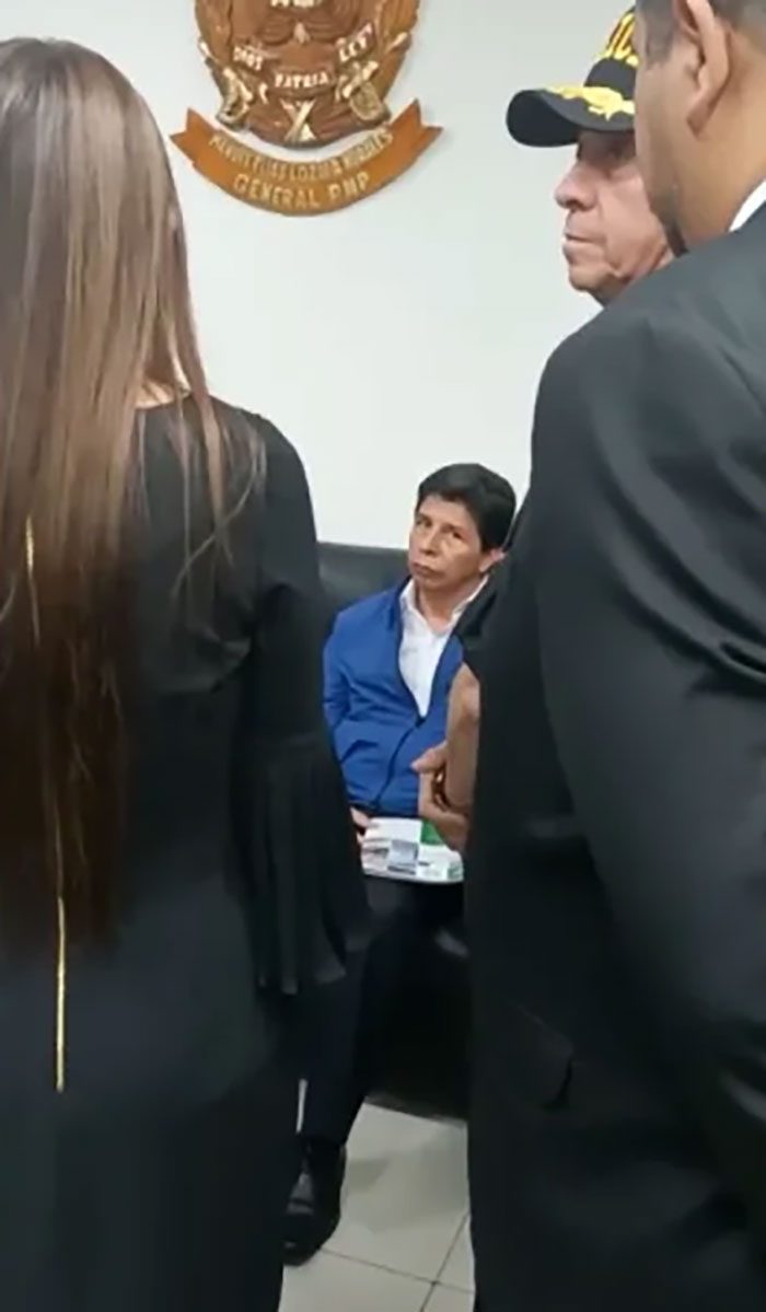 Man in blue jacket sitting looking concerned while surrounded by others in formal clothing, illustrating consequences at work.