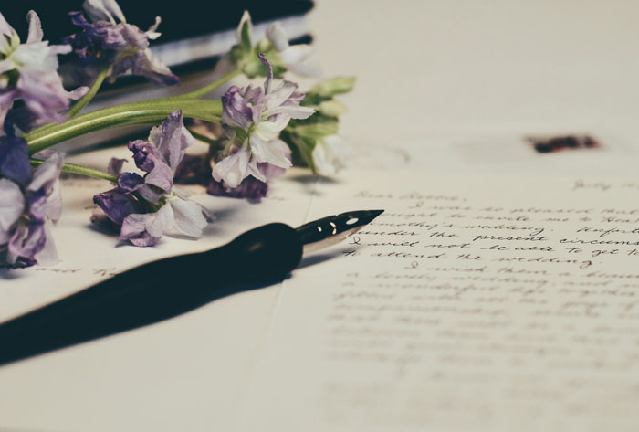 Fountain pen resting on handwritten wedding invitation paper with purple flowers symbolizing regret after accepting invitation - 9