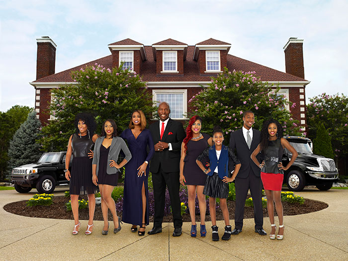 Group of well-dressed adults and children posing in front of a large house, related to former reality TV child star news.