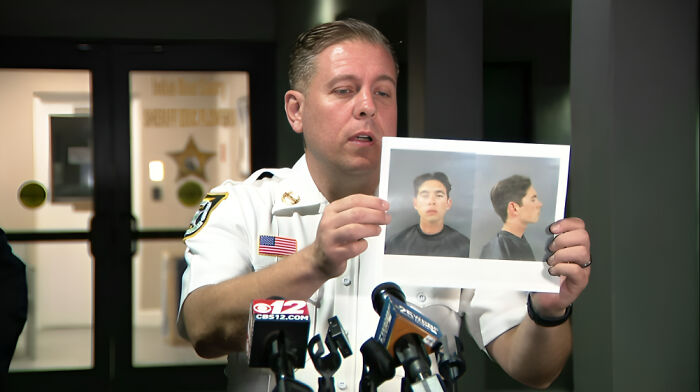 Police officer holding mugshots during a press conference about consequences of job loss due to employee mistakes.