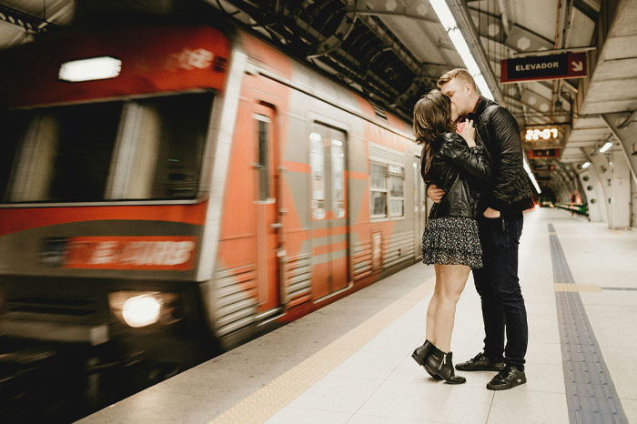 A couple kissing at a subway station with a moving train, illustrating unusual laws including a Norwegian town ban on death. - 3