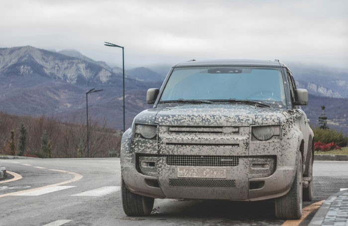 Mud-covered SUV parked on a winding road with mountains in the background, illustrating bizarre laws in a Norwegian town. - 5