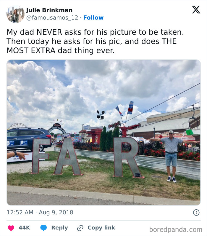 Dad posing creatively with large metal letters spelling part of FAIR at a busy outdoor fairground event.