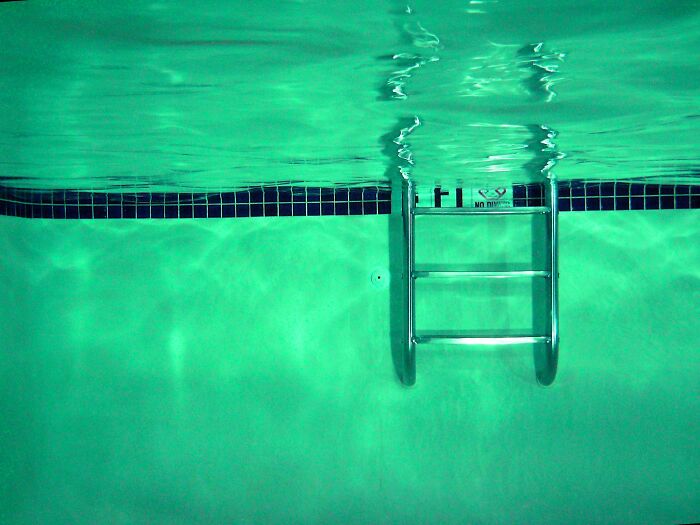 Underwater view of a pool ladder with clear green water, illustrating a rare phobia scenario involving swimming pools. - 22