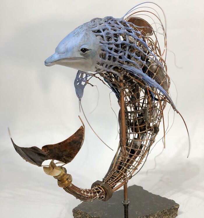 Sculpture of a dolphin made from scrap metal and gears, showcasing striking animal sculptures with intricate wire details.