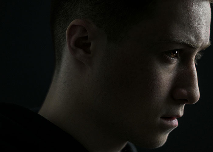 Close-up of a young man with a serious expression, illustrating red-flag argument fears in a troubled relationship.