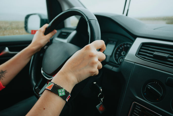 Hands gripping a steering wheel inside a car, illustrating tips to stay safe and alive while driving.