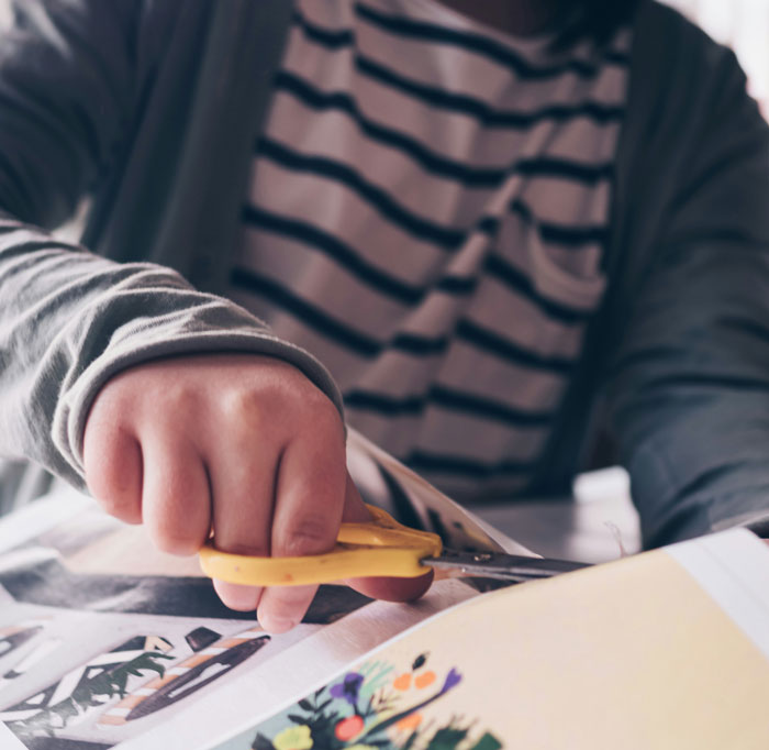 Person cutting out oldschool home trends from a magazine, highlighting millennials' shift away from traditional house styles.