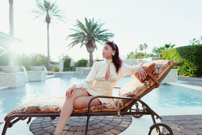 Woman relaxing by a pool on a lounge chair enjoying a luxurious lifestyle married to rich wealth and success