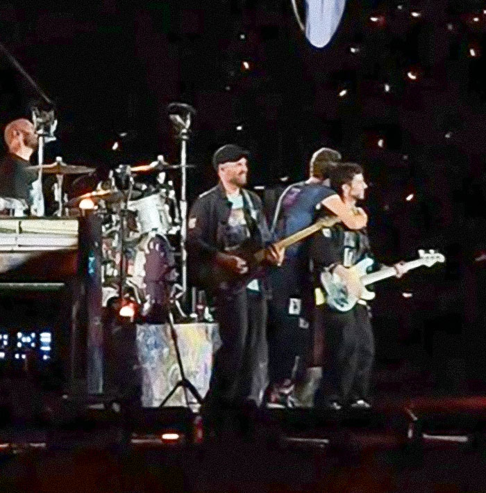 Coldplay performing on stage with the band members playing instruments during a live concert event.
