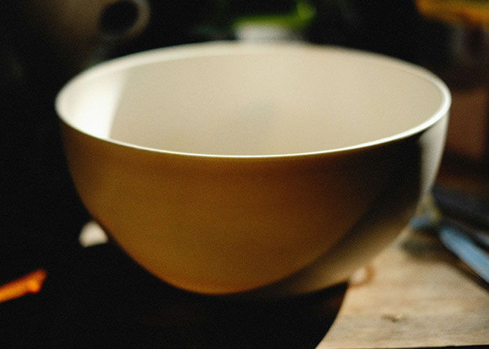 Empty ceramic bowl on wooden table, illustrating bizarre family habits shared by people as completely normal.