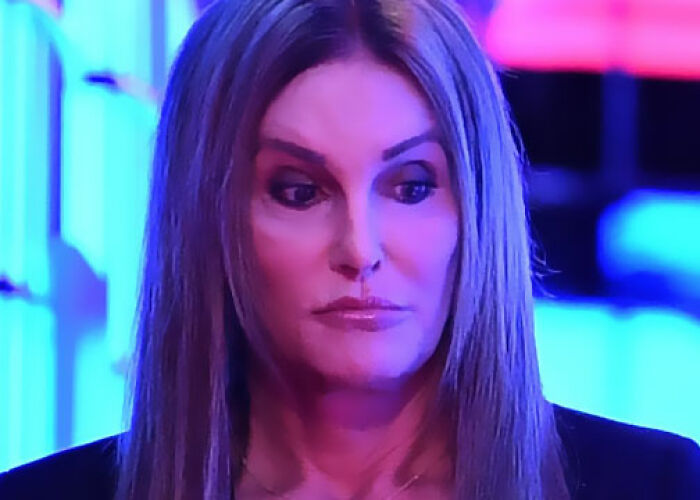 Close-up of a KarJenner clan member with long hair and serious expression under blue and pink lighting. - 21