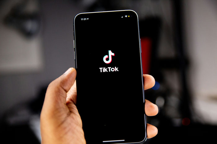 Hand holding smartphone displaying TikTok logo, illustrating cases of medical professionals disrespecting patients privacy. - 8