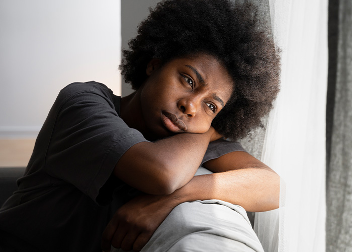 Pensive person leaning on couch near window, reflecting on former employee secrets and workplace experiences. - 10