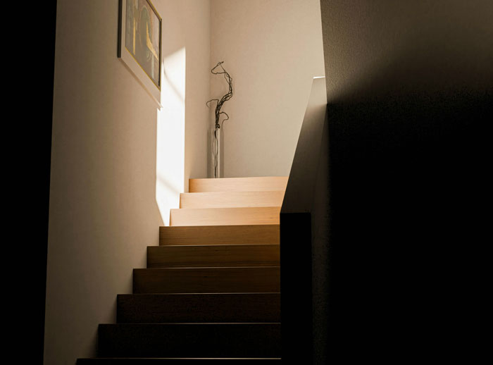 Dimly lit wooden staircase with shadows and a single vase at the top, evoking real-life horror story atmosphere. - 18