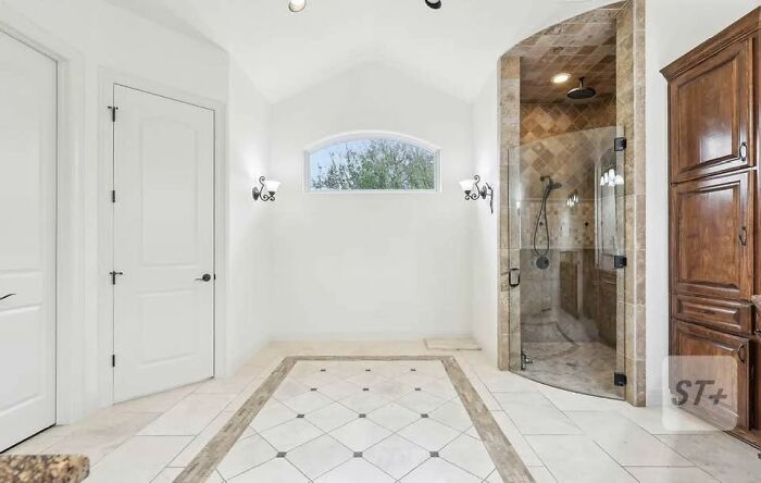 Bright bathroom with white walls, tiled floor, glass shower, wooden cabinet, showcasing creative home design attempt.