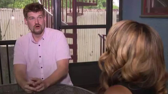 Man in pink shirt talking to woman with blonde hair at a table, illustrating people facing consequences and losing jobs.