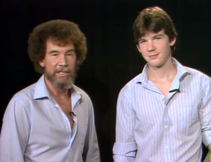 Two men in casual shirts posing against a black background in a unique old photo with an incredible story behind it.