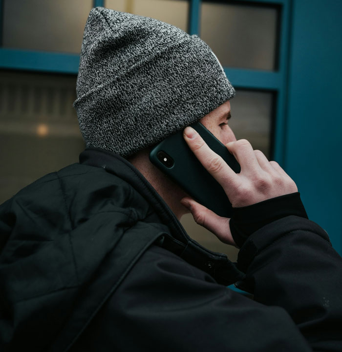 Young man in a gray beanie and black jacket speaking on a phone, reflecting estranged mom reaches out after years - 6