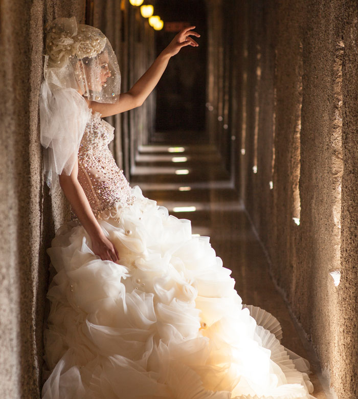 Woman in an elaborate gown and veil leaning against a stone wall, illustrating unexpected things people learned about the rich.