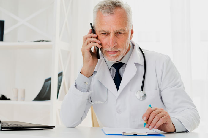 Male doctor with stethoscope on phone looking concerned with patient privacy and medical professional respect issues. - 23