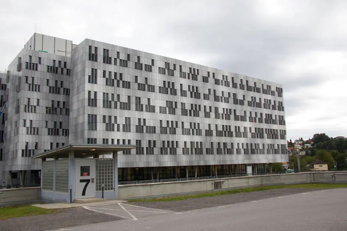 Modern office building with multiple windows under a cloudy sky, symbolizing consequences of workplace mistakes and lost jobs.