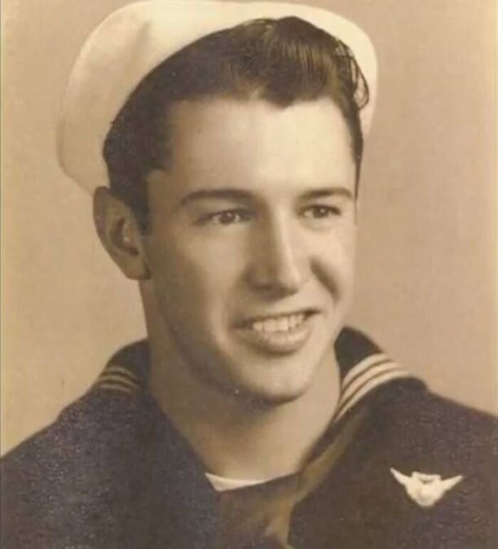 Young sailor in vintage uniform smiling in a unique old photo from the World War II era.