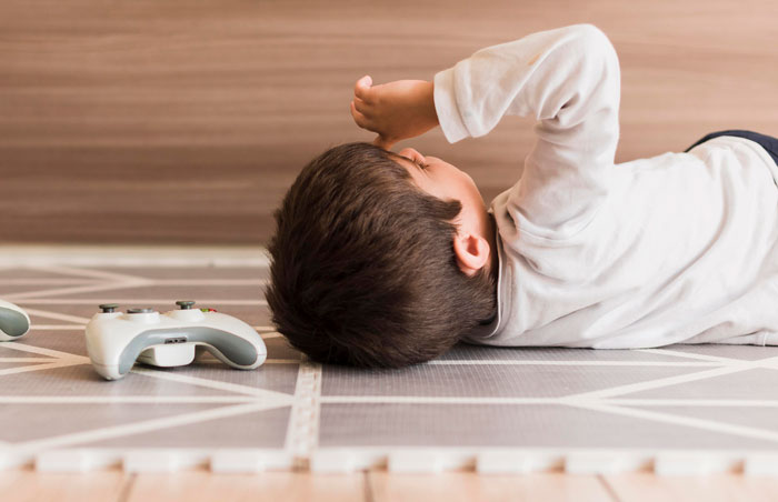 Young boy lying on floor next to video game controller, illustrating tips to stay safe and alive shared in online thread.