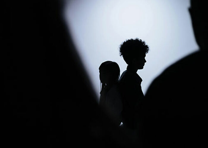 Silhouettes of two people standing back to back in a dimly lit space, hinting at tension within the KarJenner clan. - 18