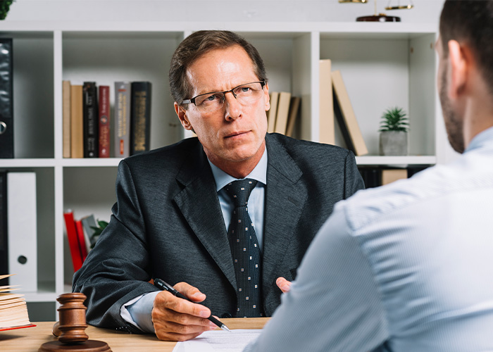 Serious businessman in glasses interviewing a former employee revealing office secrets in a modern workspace. - 6