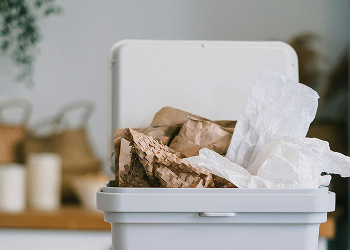 Trash bin filled with crumpled paper and bags, illustrating bizarre family habits thought normal by many people.