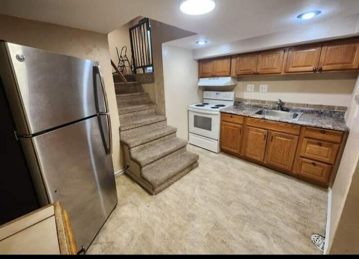 Small kitchen with stairs directly in the middle, showing a failed creative home design attempt with limited space and awkward layout.