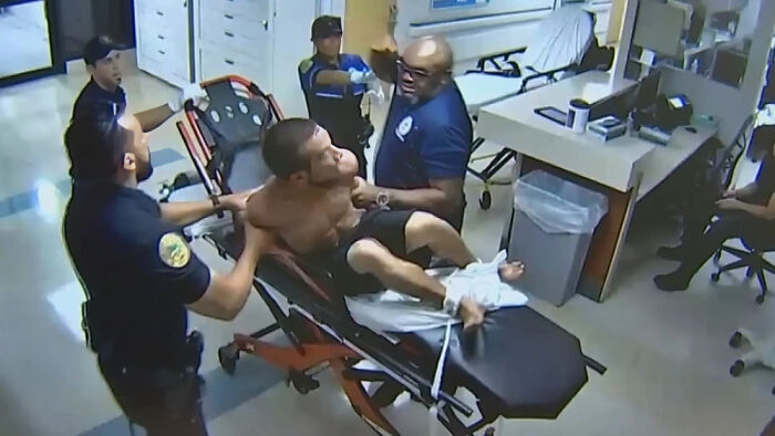 Man restrained by security guards on stretcher, depicting consequences of their own stupidity leading to job loss.