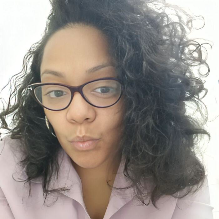 Woman with curly hair and glasses taking a close-up selfie illustrating people facing consequences of their own stupidity.