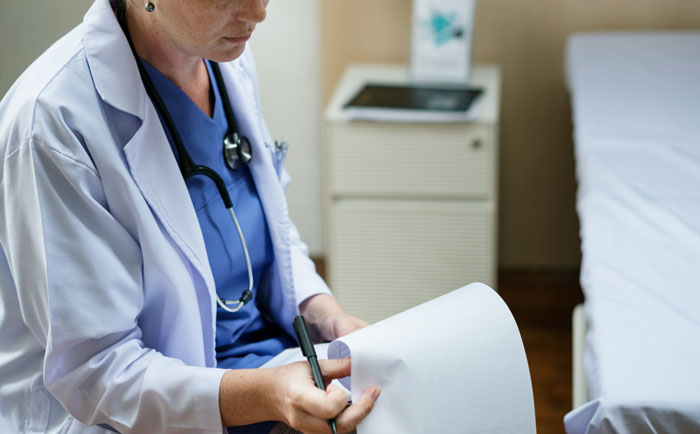 Female doctor reviewing medical papers in a hospital room, highlighting concerns about teen being taken for unnecessary hospital visits. - 6