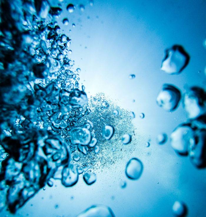 Underwater view of rising bubbles with a clear blue background illustrating tips to stay safe and alive.