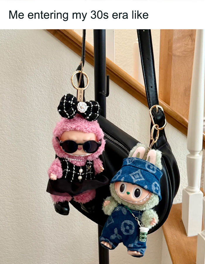 Two Labubu doll keychains dressed in trendy outfits hanging on a black purse, sparking hilarious memes online.