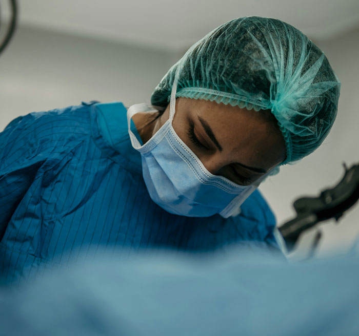 Surgeon in hospital wearing protective gear and mask, focused on procedure highlighting hospital mistakes and safety concerns.