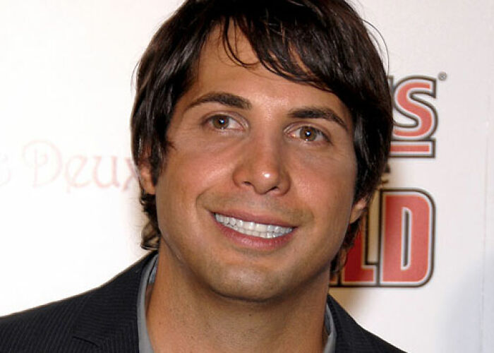 Man with dark hair and a suit smiling at an event, related to KarJenner clan controversies and worst actions. - 11