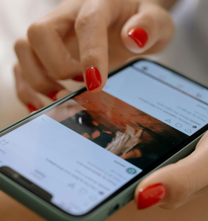 Person with red nails scrolling on a smartphone, illustrating issues of medical professionals disrespecting patient privacy. - 22